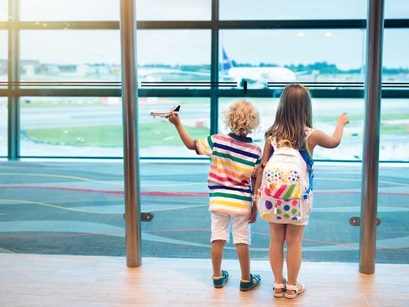 Two young children at an airport window – legal support for moving abroad with my child.