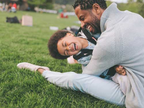 Father playing and laughing with child in a park – contact with my child legal advice and support.